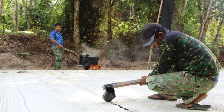 Anggota Satgas TMMD Lapisi Sambungan Semenisasi Jalan dengan Cairan Aspal
