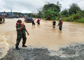Wilayah Binaan Terendam Banjir, Babinsa Teluk Pandan Lakukan Pengaturan Lalin